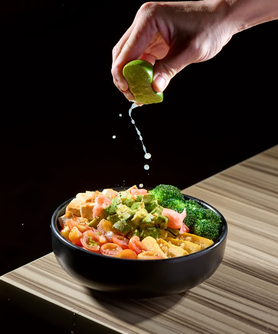 A hand squeezing a lime over a finished bowl, the last thing in
